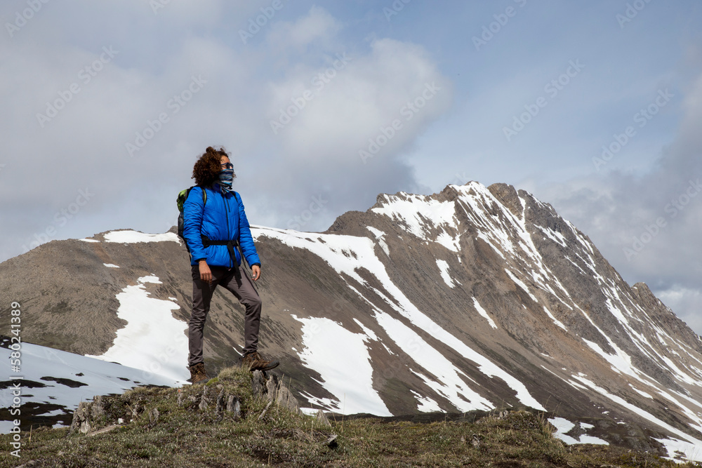 Full length of hiker with scarf covering mouth looking at view against mountains Full length of hiker with scarf covering mouth looking at view against mountains