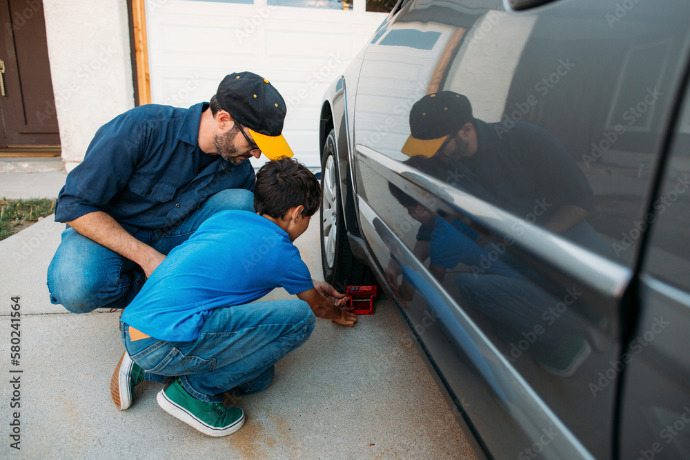 Father and son adjusting car stopper on wheel at driveway Father and son adjusting car stopper on wheel at driveway