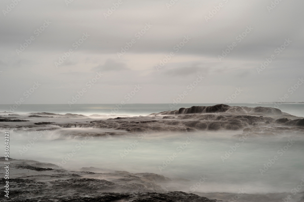 Tranquil view of rocks in sea against cloudy sky