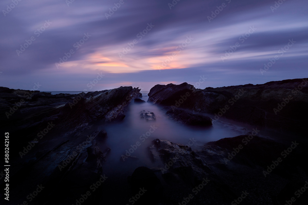 Idyllic view of rocks on shore against dramatic sky Idyllic view of rocks on shore against dramatic sky