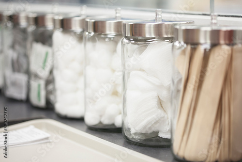 Close-up of cotton balls, medicines and tongue depressors in canisters at medical clinic