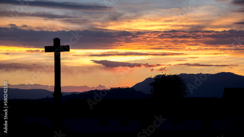 Silhouette cross against cloudy sky during sunset
