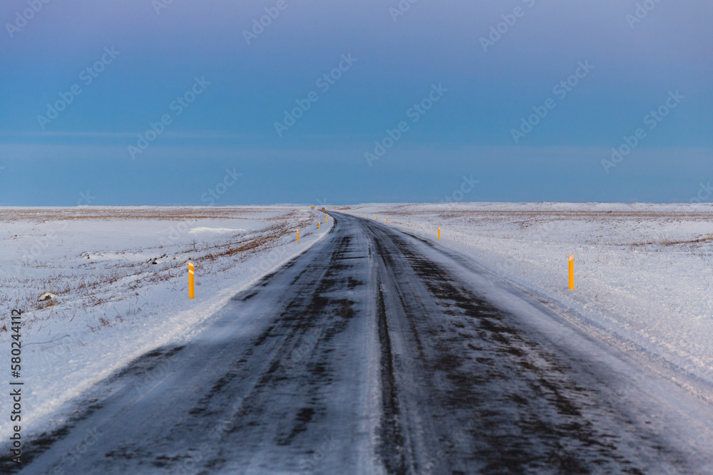 Country road amidst snowy field against sky Country road amidst snowy field against sky