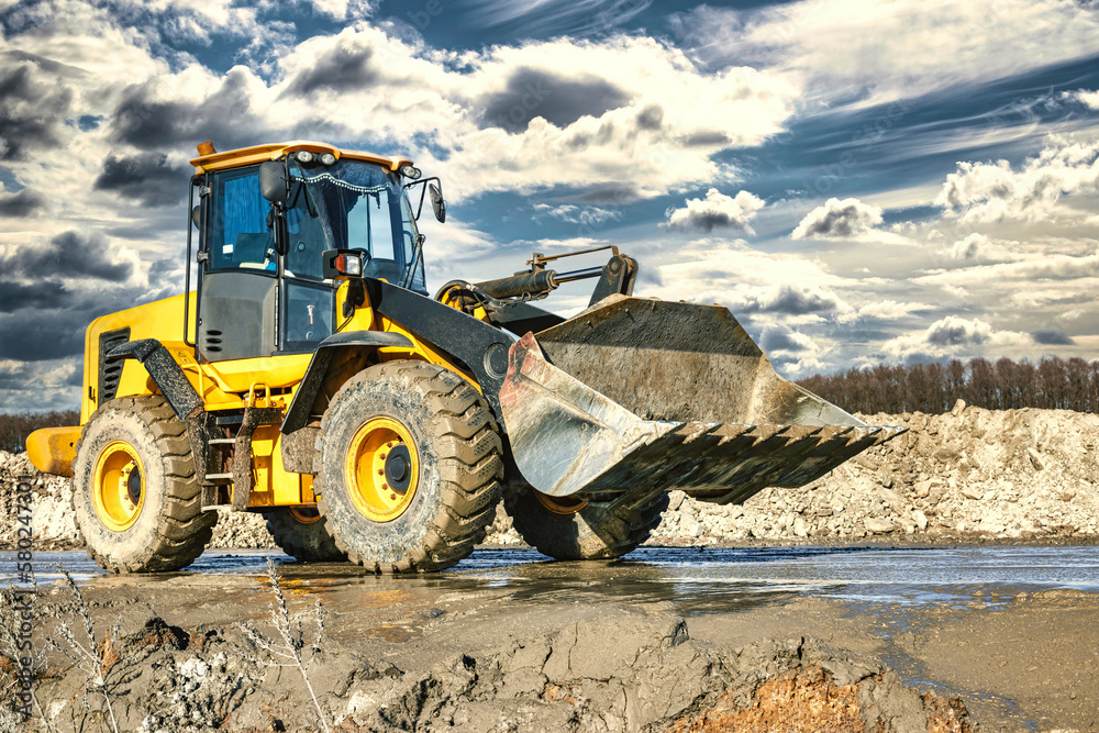 Powerful wheel loader or bulldozer working on a quarry or construction site. Earthworks in construction. Powerful modern equipment for earthworks. Powerful wheel loader or bulldozer working on a quarry or construction site. Earthworks in construction. Powerful modern equipment for earthworks.