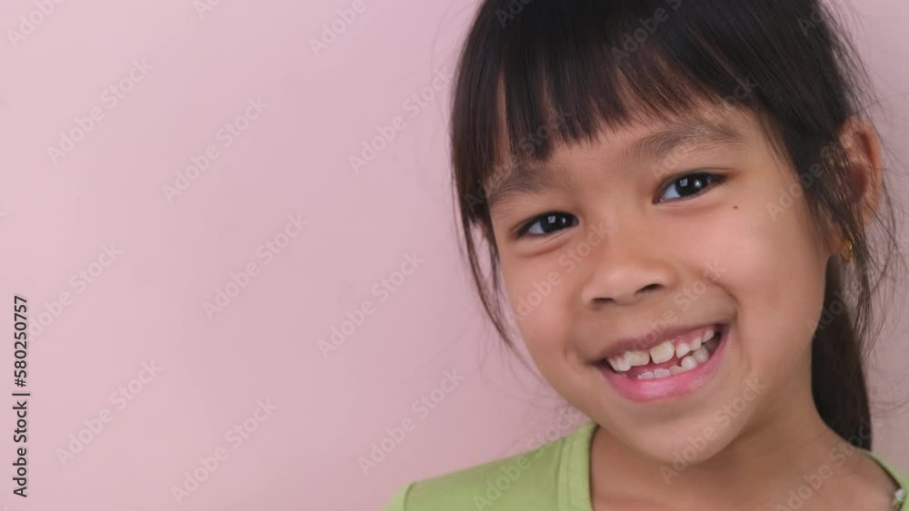 Portrait of happy smiling girl isolated on pink background in studio. Funny little girl smiling looking at camera at home. Concept of happy childhood Portrait of happy smiling girl isolated on pink background in studio. Funny little girl smiling looking at camera at home. Concept of happy childhood