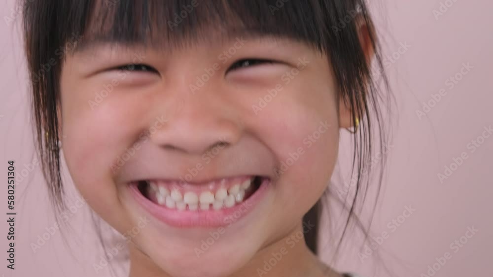 Portrait of happy smiling girl isolated on pink background in studio. Funny little girl smiling looking at camera at home. Concept of happy childhood Portrait of happy smiling girl isolated on pink background in studio. Funny little girl smiling looking at camera at home. Concept of happy childhood