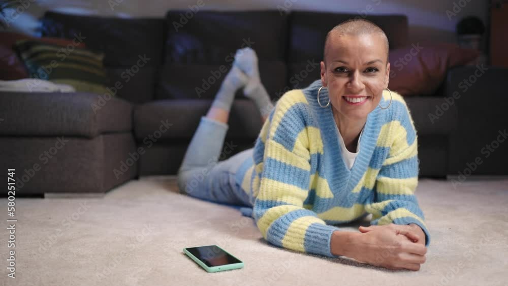 Portrait of trendy smiling woman with shaved hair lying on carpet at cozy home Portrait of trendy smiling woman with shaved hair lying on carpet at cozy home
