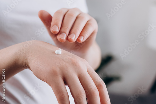 Close up of unrecognizable young caucasian woman applying cream on hand skin, enjoy natural beauty and healthy clean soft moisturized hydrated skin care treatment. Female hands care. Medical concept
