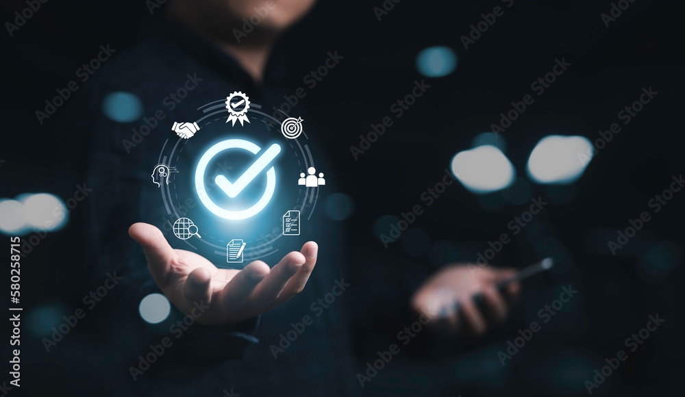 Businessman holding glowing correct sign mark with quality icon for ...