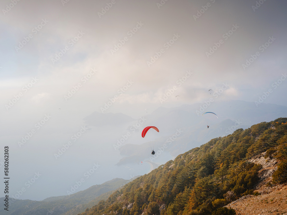 Paragliding in sky. Paraglider tandem flying over sea and mountains in cloudy day. view of paraglider and Blue Lagoon in Oludeniz, Turkey. Extreme sport. Landscape Paragliding in sky. Paraglider tandem flying over sea and mountains in cloudy day. view of paraglider and Blue Lagoon in Oludeniz, Turkey. Extreme sport. Landscape