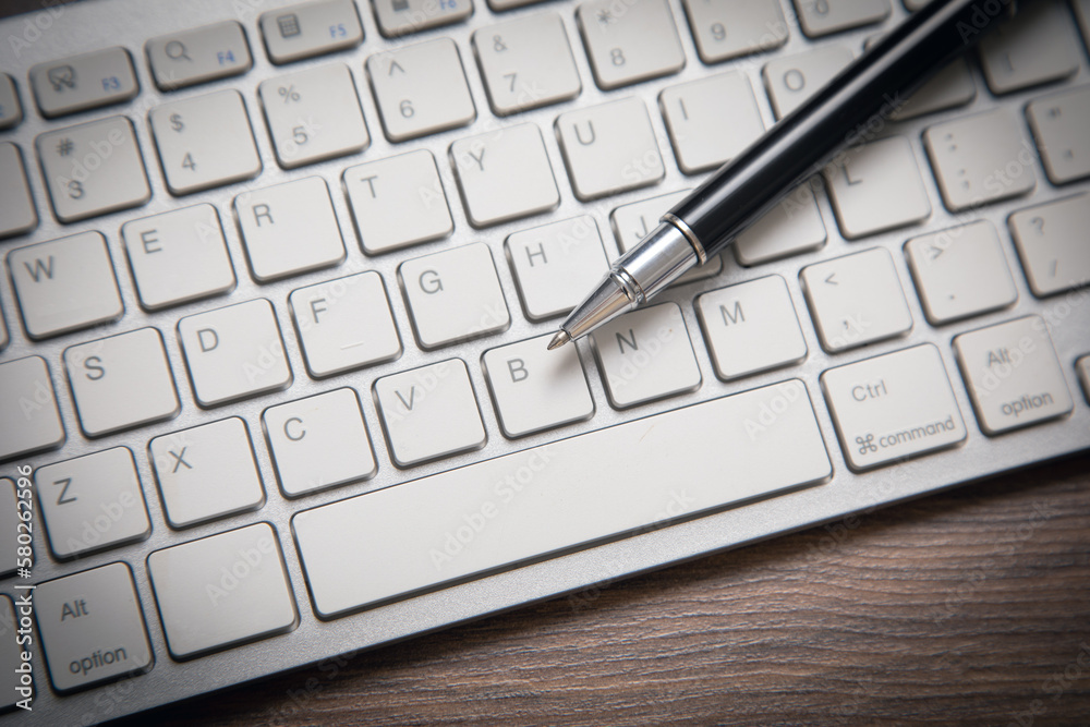 Black pen on the computer keyboard. Black pen on the computer keyboard.