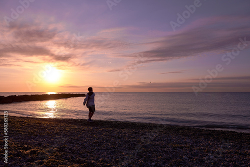 Boy playing pebble throwing on the beach at dawn
