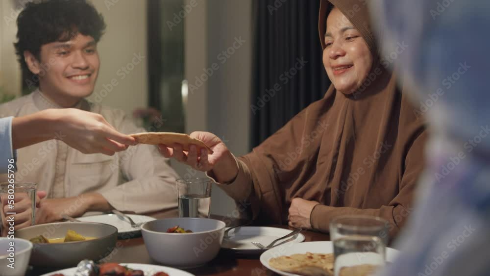 Eid Mubarak Muslim Asia family have Iftar dinner sister share bread to sibling for break fasting. Traditional food during Ramadan month at home, The Islamic Halal Eat and Drink at modern Islam. Eid Mubarak Muslim Asia family have Iftar dinner sister share bread to sibling for break fasting. Traditional food during Ramadan month at home, The Islamic Halal Eat and Drink at modern Islam.