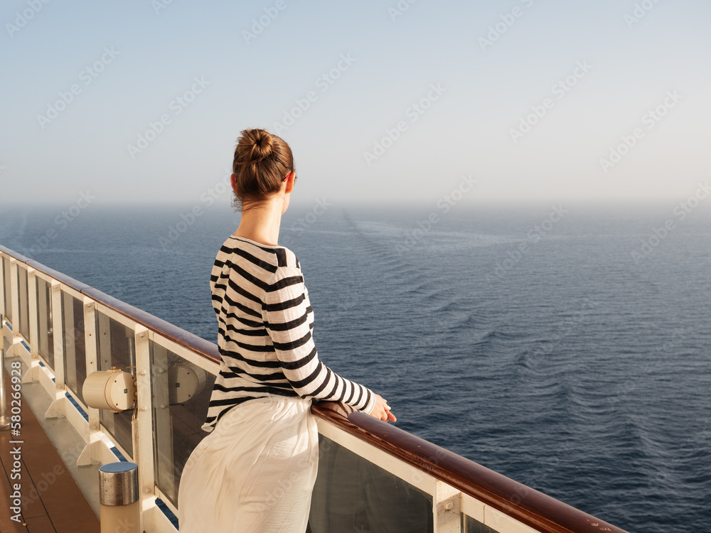 Stylish woman standing on the empty deck of a cruise ship. Sunny morning, clear day. Closeup, outdoors. Vacation and travel concept
