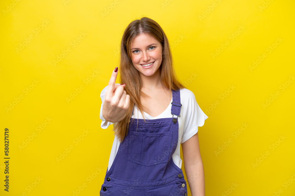Young caucasian woman isolated on yellow background doing coming gesture Young caucasian woman isolated on yellow background doing coming gesture