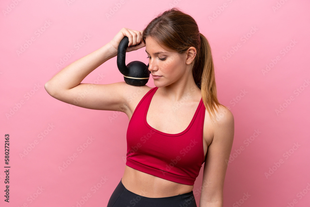 Young caucasian woman isolated on pink background making weightlifting with kettlebell Young caucasian woman isolated on pink background making weightlifting with kettlebell