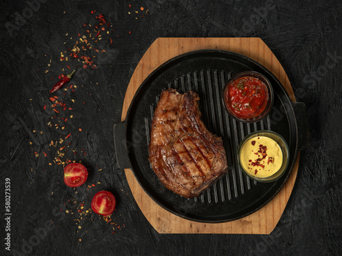 pork steak with vegetables in a black iron pan , top view.