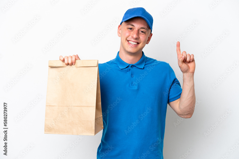 Young Brazilian man taking a bag of takeaway food isolated on white background pointing up a great idea Young Brazilian man taking a bag of takeaway food isolated on white background pointing up a great idea