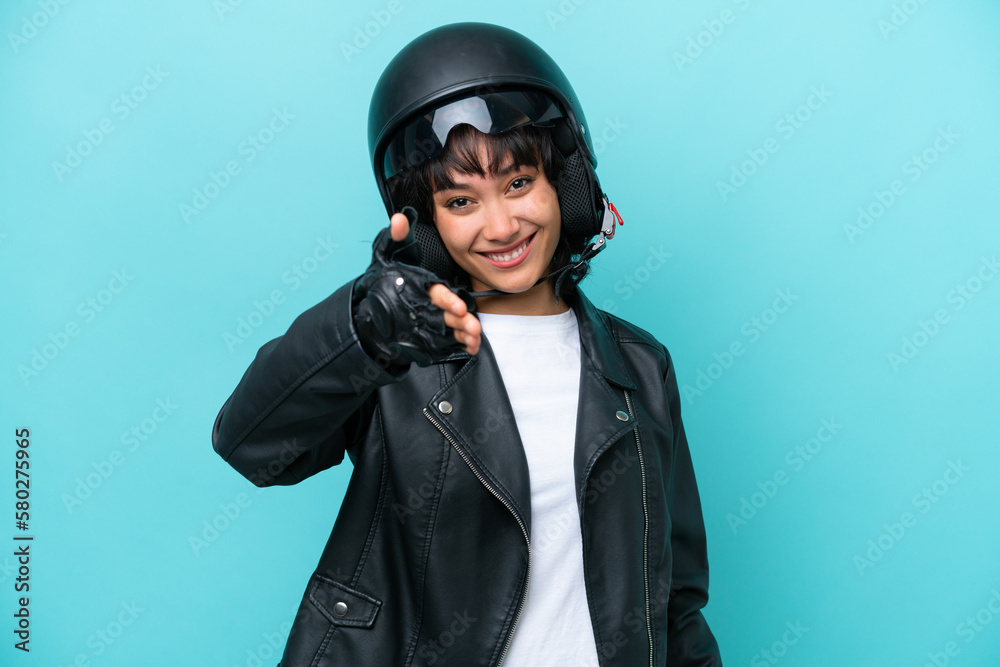 Young Argentinian woman with a motorcycle helmet isolated on blue background shaking hands for closing a good deal Young Argentinian woman with a motorcycle helmet isolated on blue background shaking hands for closing a good deal