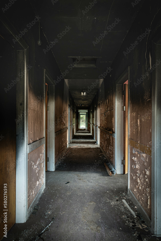 Abandoned derelict Hospital corridor, with peeling paint and black water stains on the walls from water damage.