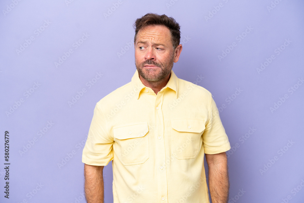 Middle age caucasian man isolated on purple background making doubts gesture looking side Middle age caucasian man isolated on purple background making doubts gesture looking side