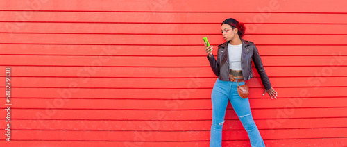 urban girl with mobile phone and red wall background