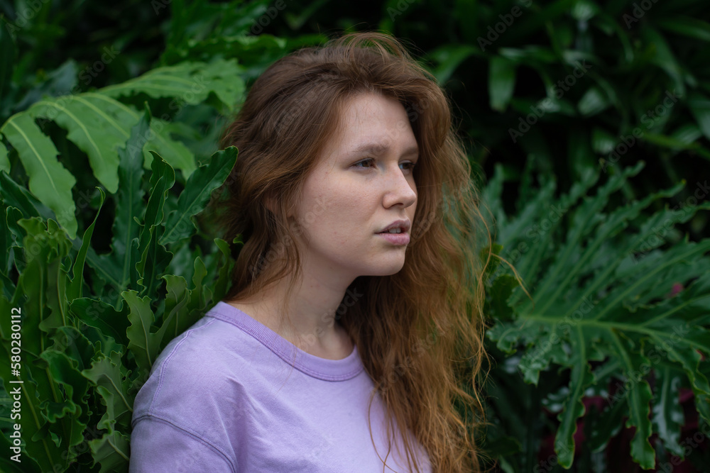Portrait of young woman standing on an ivy, fern wall or in greenery, breathing, smiling and looking away girl relaxing outdoors at summer day.Love for nature, eco life,green leaves, green park Portrait of young woman standing on an ivy, fern wall or in greenery, breathing, smiling and looking away girl relaxing outdoors at summer day.Love for nature, eco life,green leaves, green park