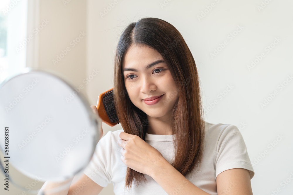 Woman looking in the mirror and combing her hair. Woman looking in the mirror and combing her hair.