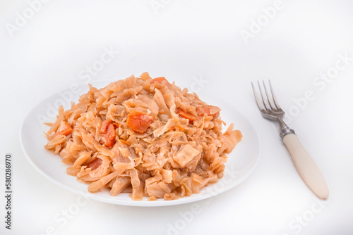 Stewed cabbage - bigos in a white plate on a light background. Close-up photo