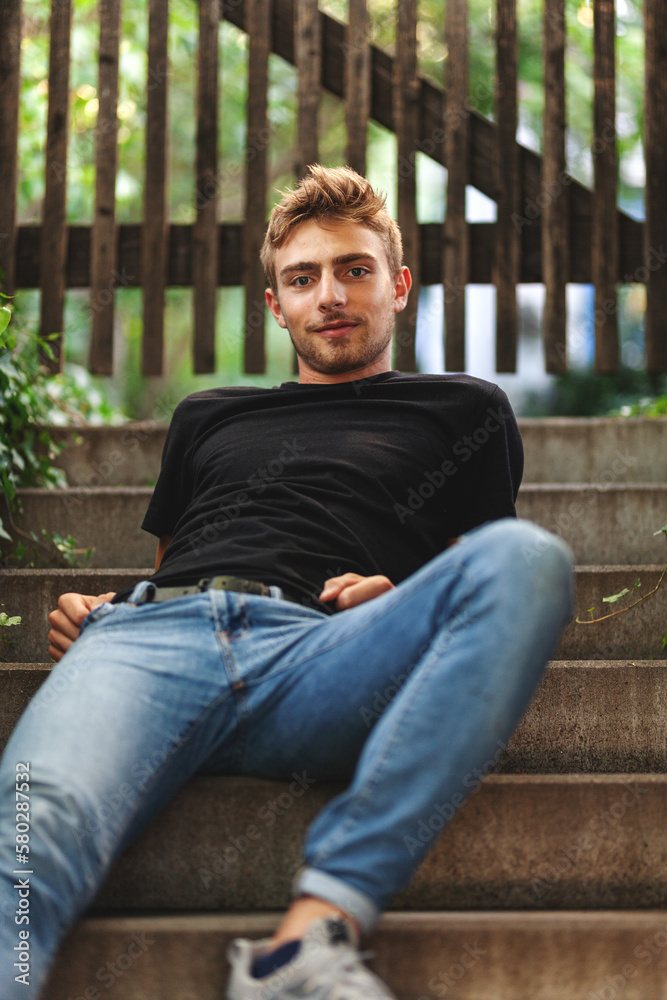 Obraz premium gut aussehender, junger Mann sitzt nachdenklich auf einer Treppe mit aufgestütztem Kopf, traurig, depressiv