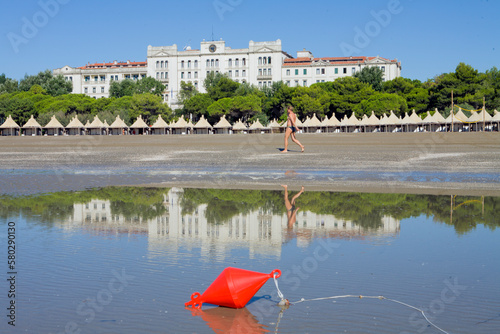 Lido di Venezia. Boa sul bagna suga della spiaggia del Des Bains con tukuls e riflesso in acqua photo