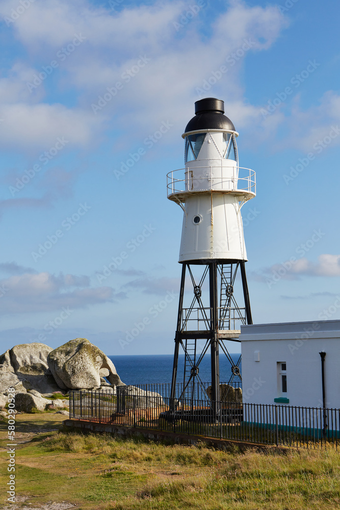 Isles of Scilly, United Kingdom -  Peninnis Lighthouse on a sunny autumn day with rocks and sea and grass. vertical image
