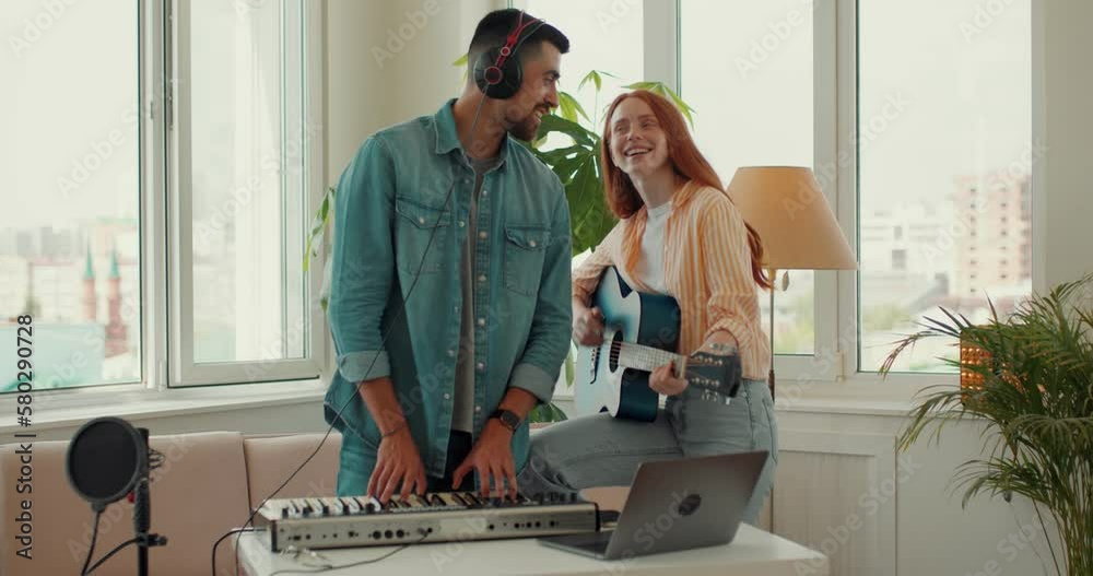 Happy bearded talented man playing piano, red-haired woman playing guitar at home, singing songs, having fun at studio. lifestyle, free spare time, hobby, interests, slow motion,music lovers Happy bearded talented man playing piano, red-haired woman playing guitar at home, singing songs, having fun at studio. lifestyle, free spare time, hobby, interests, slow motion,music lovers