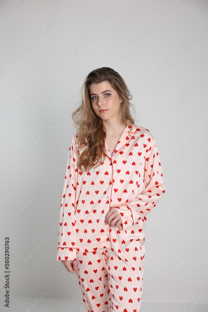 beautiful blonde girl on a white background in pajamas. pajamas with hearts. romantic pajamas. Valentine's Day. studio photo shoot in satin pajamas with a heart print. clothes for sleep and home beautiful blonde girl on a white background in pajamas. pajamas with hearts. romantic pajamas. Valentine's Day. studio photo shoot in satin pajamas with a heart print. clothes for sleep and home