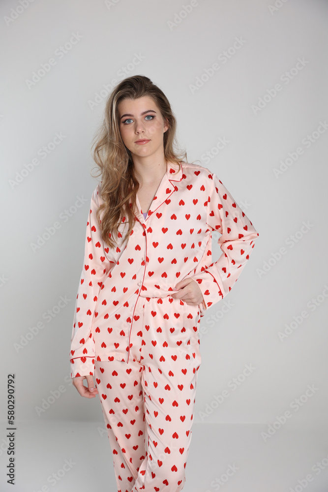 beautiful blonde girl on a white background in pajamas. pajamas with hearts. romantic pajamas. Valentine's Day. studio photo shoot in satin pajamas with a heart print. clothes for sleep and home beautiful blonde girl on a white background in pajamas. pajamas with hearts. romantic pajamas. Valentine's Day. studio photo shoot in satin pajamas with a heart print. clothes for sleep and home