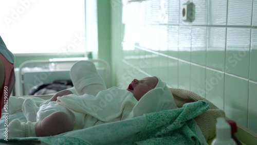 A doctor without gloves draws a vaccine into a syringe for an injection to a newborn child. A newborn baby is screaming in the background. Vaccination in the hospital. Violation of sanitary standards