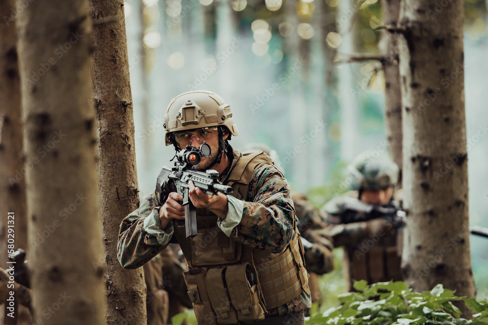 Fototapeta premium A group of modern warfare soldiers is fighting a war in dangerous remote forest areas. A group of soldiers is fighting on the enemy line with modern weapons. The concept of warfare and military