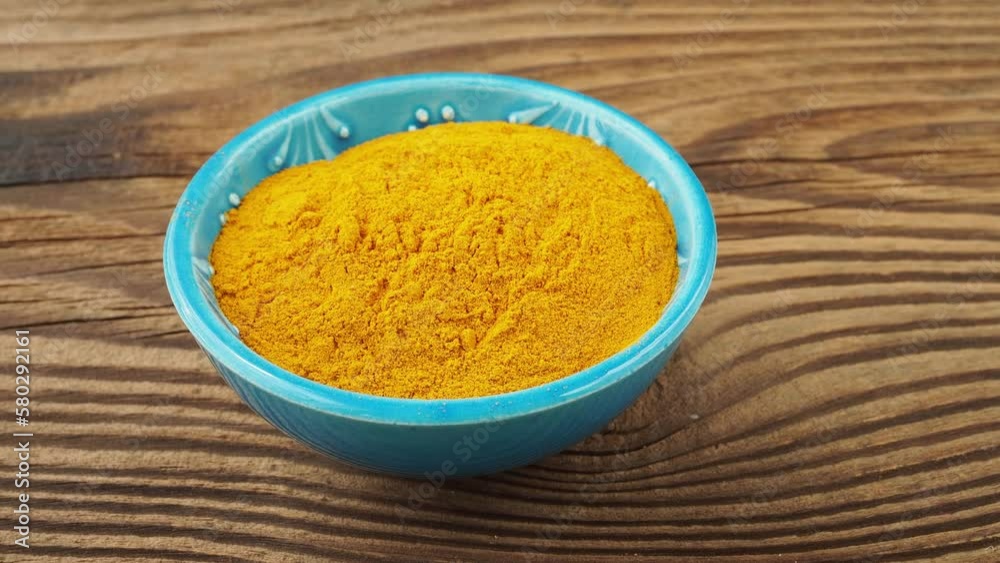 Curcuma powder in a small bowl on the table Curcuma powder in a small bowl on the table