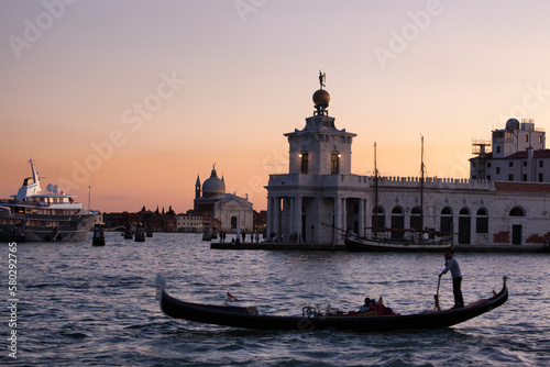 Venezia. Gondoliere in transito a Punta della Dogana con il Redentore al tramonto. © Guido