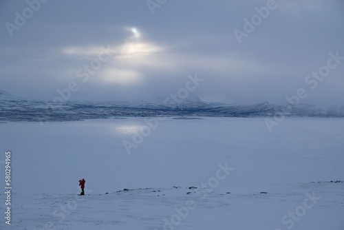 Silhouette of person on snowshoes bank of lake Torneträsk (Tornestrask) around Abisko National Park (Abisko nationalpark) in misty winter scenery. Sweden, Arctic Circle, Swedish Lapland