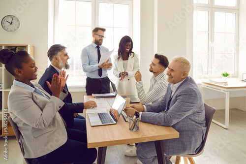 Diverse corporate business team having fun during a work meeting. Group of happy young and senior multiethnic people sitting at an office table and laughing at something funny
