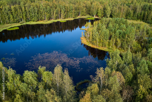Aerial view of a picturesque landscape with a peat lake and a small island surrounded by green forest