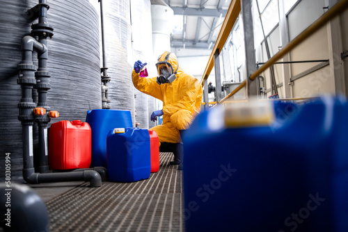 Chemical factory worker testing quality of chemicals. Industrial interior.
