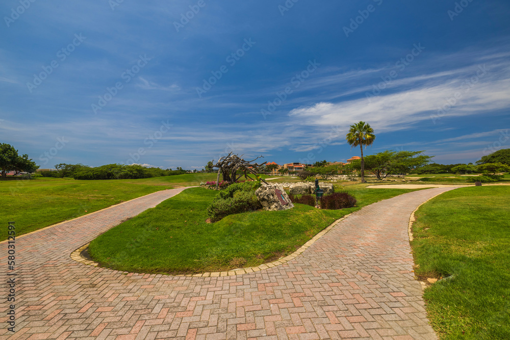 Beautiful view of golf course with paved road for driving electric golf car. Aruba. Beautiful view of golf course with paved road for driving electric golf car. Aruba.
