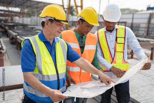 Portrait Asia man and team engineer hard working with paper work at precast cement factory 