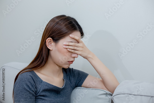 Female having depression sitting alone on sofa. woman her face covered with headache. unhappy emotion. young anxiety despair mental health problems.