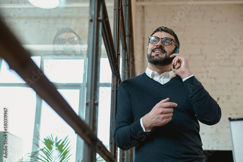 Smiling adult man making phone call in the office