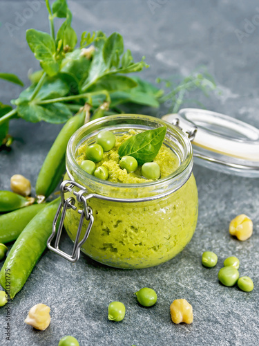 Hummus from green peas in jar on stone table