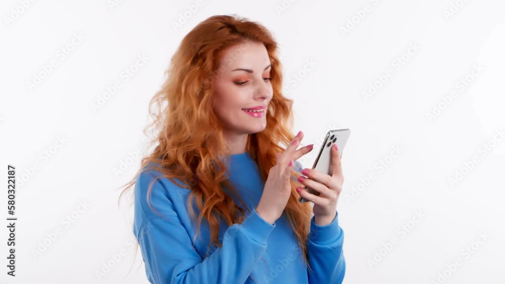 Young woman smiling with smart phone, positive confidence. Happy positive emotional pretty lady mobile phone looking at mobile. Indoors studio, pretty lady isolated on white background Young woman smiling with smart phone, positive confidence. Happy positive emotional pretty lady mobile phone looking at mobile. Indoors studio, pretty lady isolated on white background