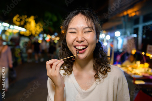 Beautiful young Asian tourist woman on vacation sightseeing and exploring at Khao San road at night in Bangkok city  Thailand  Holidays and traveling concept